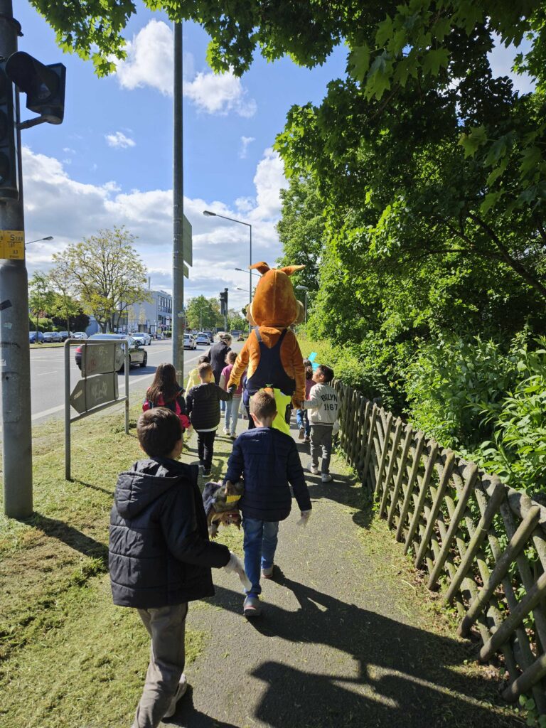 Gruppe von Kindern geht mit Lutz van Putz die Straßen entlang.